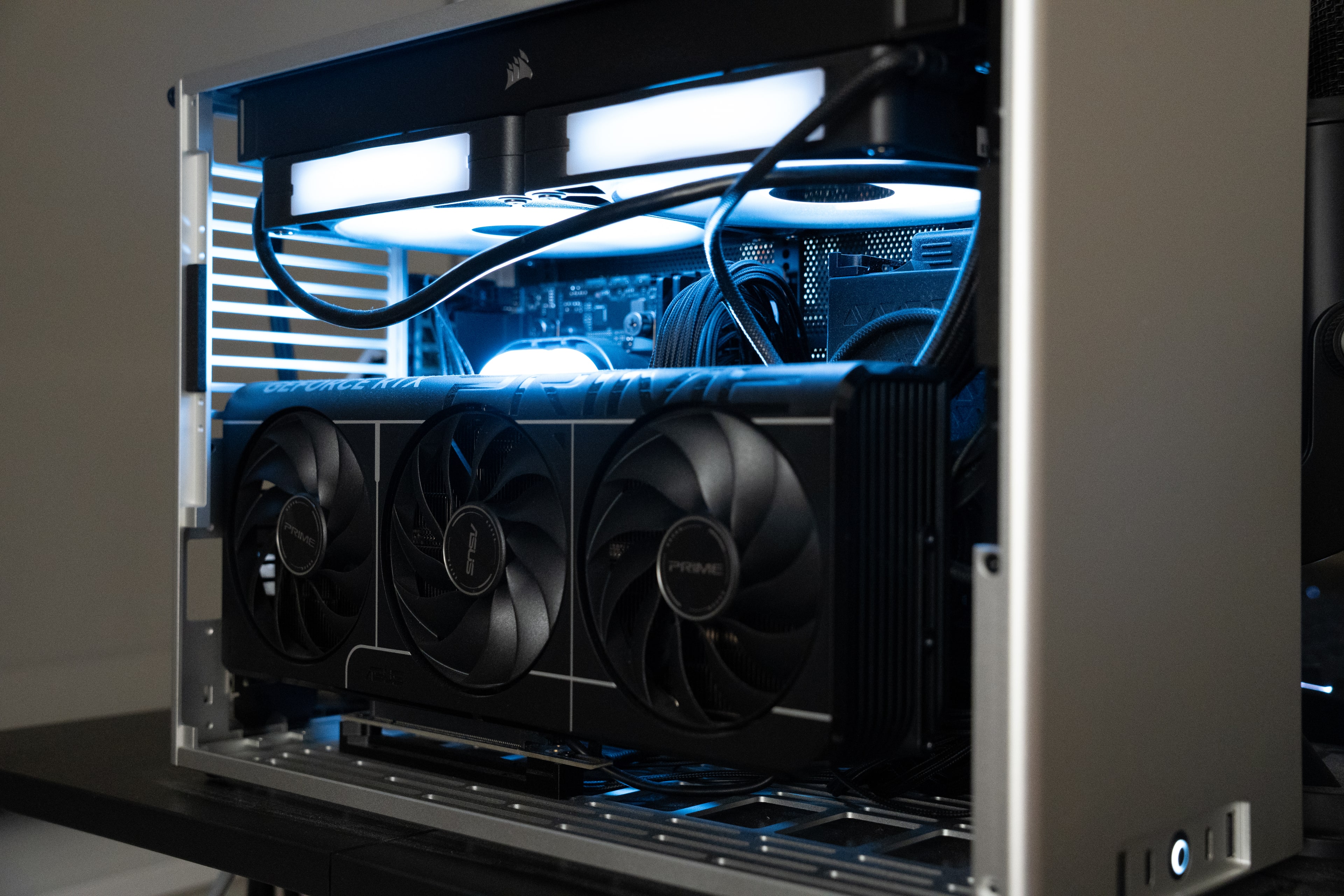 A small-form-factor computer in an open aluminium frame, the graphics card and liquid-cooling loop lit from within in blue.
