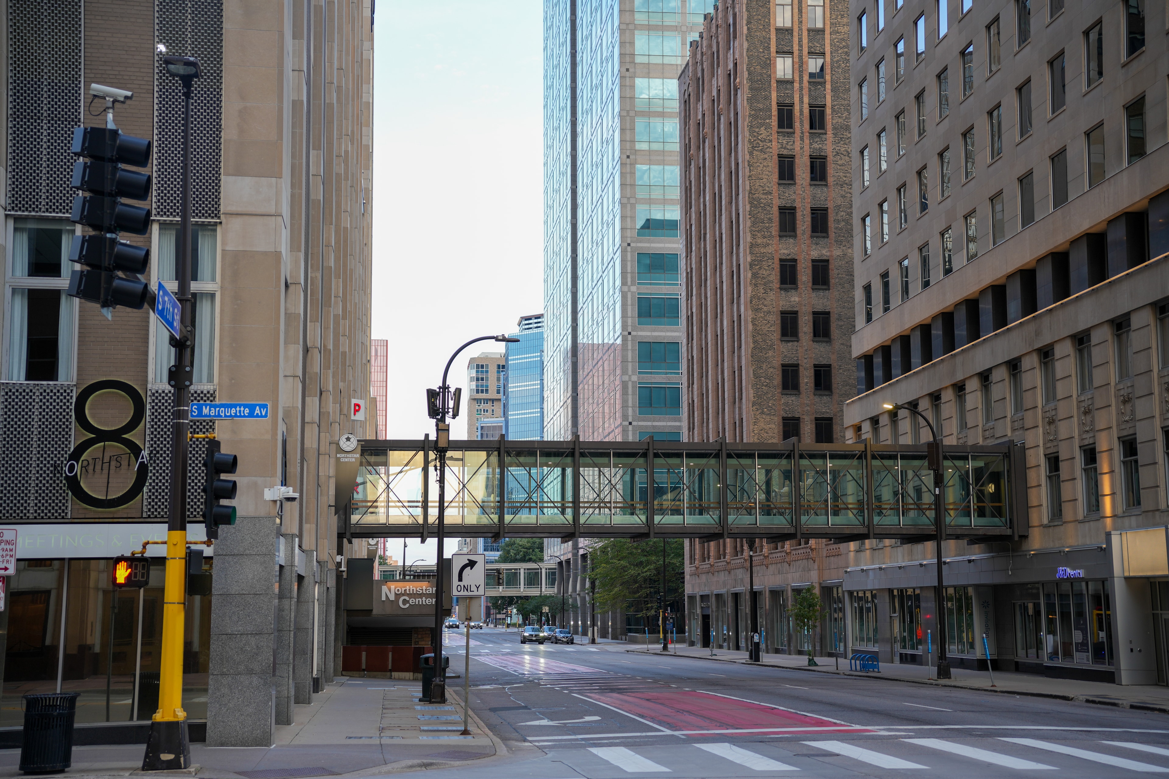 A glass skyway bridging two towers above an empty street, catching the last of the evening light.